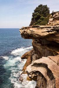 Rock formation on beach against sky