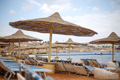 Lounge chairs and parasols on beach against sky