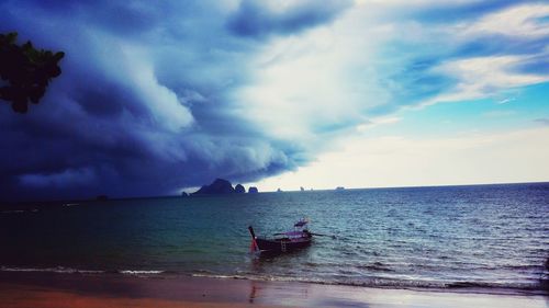 Boat sailing in sea against cloudy sky