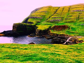 Scenic view of cliff by sea against clear sky