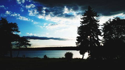 Silhouette trees by lake against sky during sunset