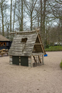 Wooden house amidst trees on field