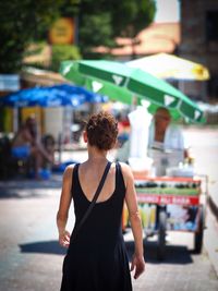 Rear view of woman standing on city street during summer