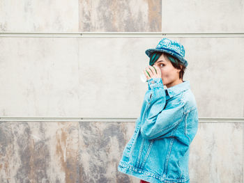 Full length of teenage girl standing against wall