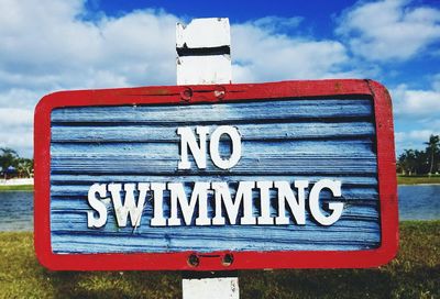 Close-up of signboard against cloudy sky
