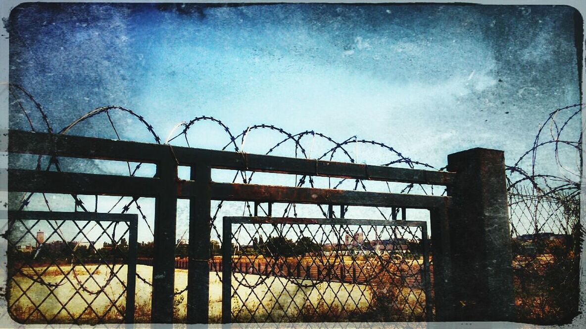 sky, fence, transfer print, cloud - sky, metal, auto post production filter, built structure, protection, low angle view, safety, architecture, security, cloud, tree, bare tree, cloudy, metallic, silhouette, outdoors, chainlink fence