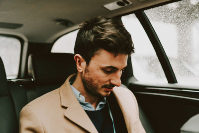 Close-up of businessman using phone while traveling in car