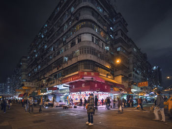 People on street against illuminated buildings in city at night