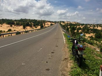 Rear view of people riding motorcycle on road against sky