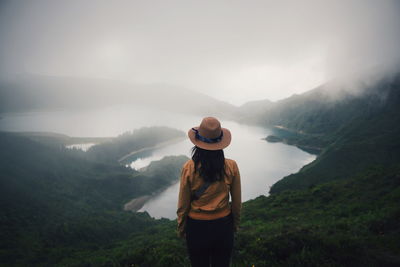 Woman standing on mountain during foggy weather
