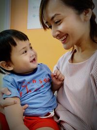 Happy mother and son looking each other face to face at home