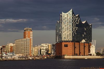 Modern buildings by sea against sky in city