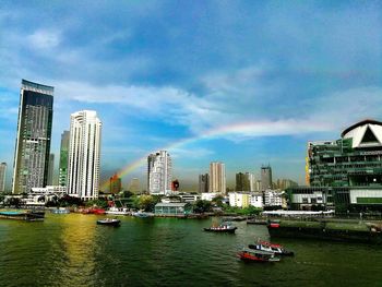 Boats in city by buildings against sky