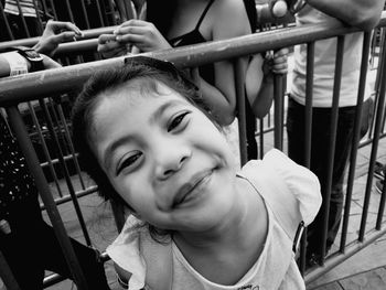 Portrait of cute girl smiling while standing by railing