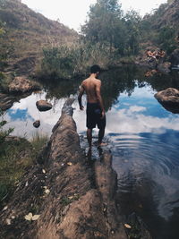 Rear view full length of shirtless man standing in pond