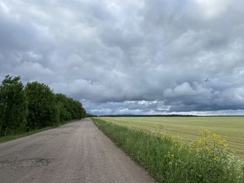 Road amidst field against sky