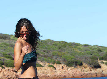 Woman wearing bikini while standing against clear blue sky