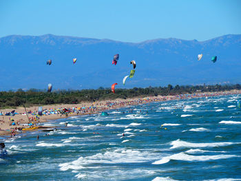 People enjoying at beach against blue sky