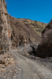 Dirt road amidst mountains against clear sky