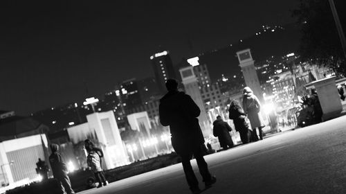 Rear view of man and woman on road at night