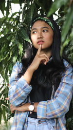 Beautiful young woman standing by tree