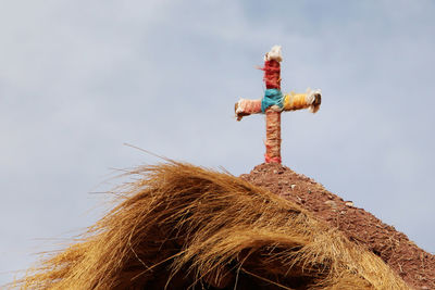 Low angle view of cross on roof against sky