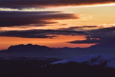 Scenic view of silhouette mountains against orange sky