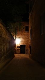 Empty alley amidst buildings at night