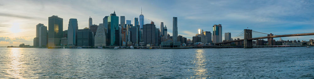 City at waterfront against cloudy sky