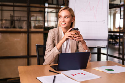 Young woman using mobile phone while sitting on table