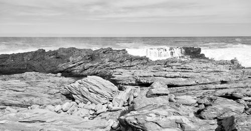 Rock formation on beach against sky