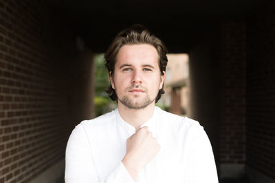 Portrait of young man standing against wall