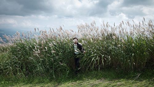 Man walking along long grass on landscape