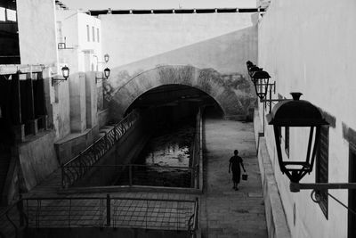 Rear view of man walking on path against building