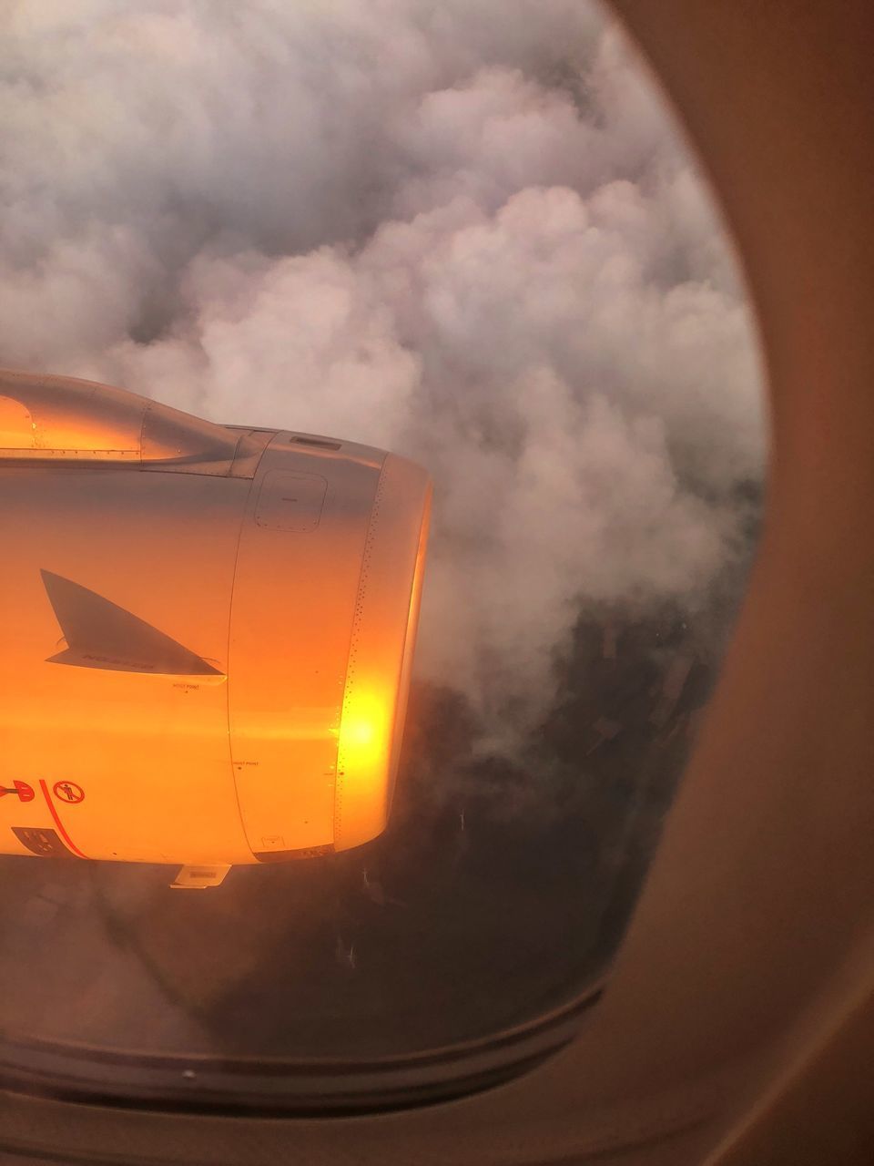 CLOSE-UP OF AIRPLANE WINDOW AGAINST ORANGE SKY