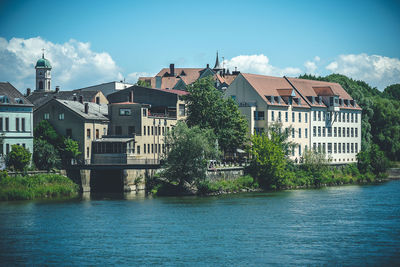 Buildings by river against sky