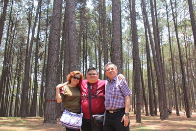 Friends smiling amidst trees in forest