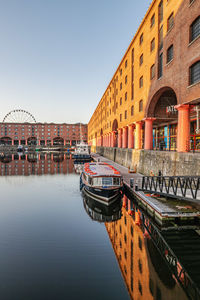 Boats moored in canal by buildings against clear sky