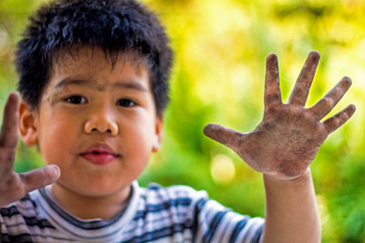 Close-up portrait of boy showing dirty hands