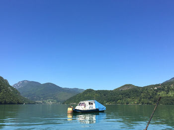 Scenic view of lake and boat against clear blue sky