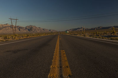 Empty road at desert against clear blue sky