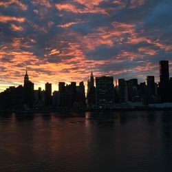 River by urban skyline at manhattan against cloudy sky during sunset