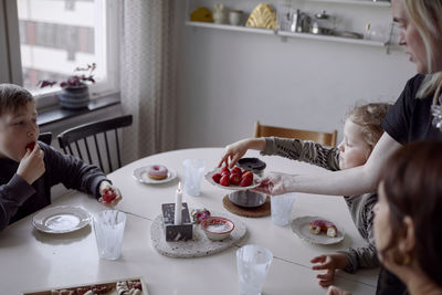 Family sitting at table and eating strawberries