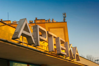 Low angle view of yellow building against clear blue sky