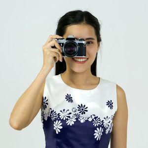 Portrait of young woman photographing against white background