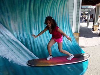 Optical illusion of woman with arms outstretched surfboarding