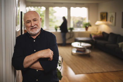 Portrait of confident senior man standing at home