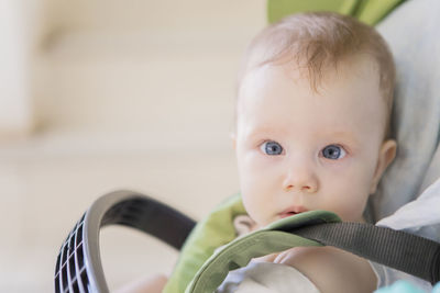 Close-up portrait of cute baby girl sitting in carriage at home