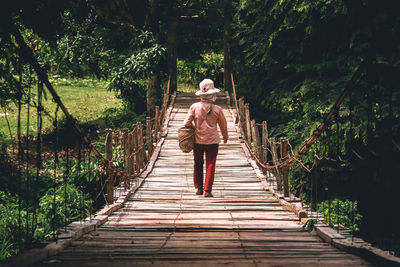 Full length of man walking on footbridge in forest