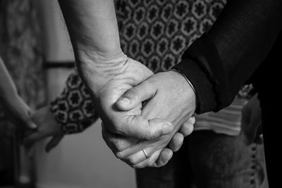 Friends holding hands while standing at home